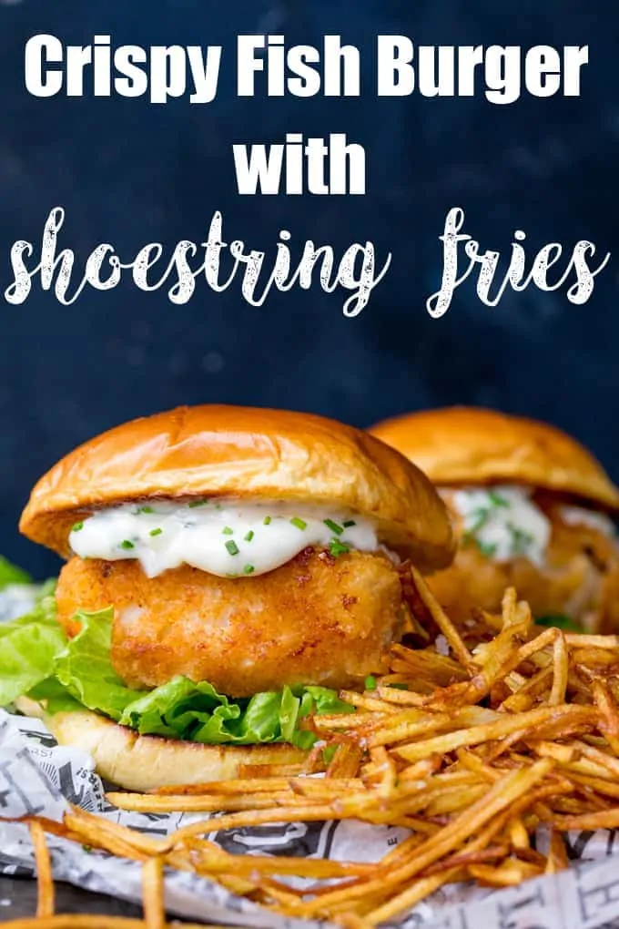 Breaded haddock burger on brioche bun with lettuce and chive-speckled mayonnaise. Shoestring fries to the right of the burger. A second burger in background.