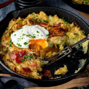 bubble and squeak in a pan with a portion taken out. Running poached egg on top