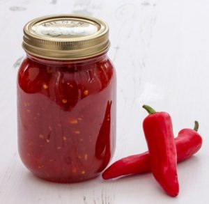 Jar of sweet chilli jam on white background