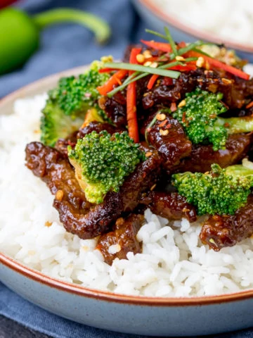 Bowl of rice topped with crispy beef strips in a tangy spicy sauce with broccoli.