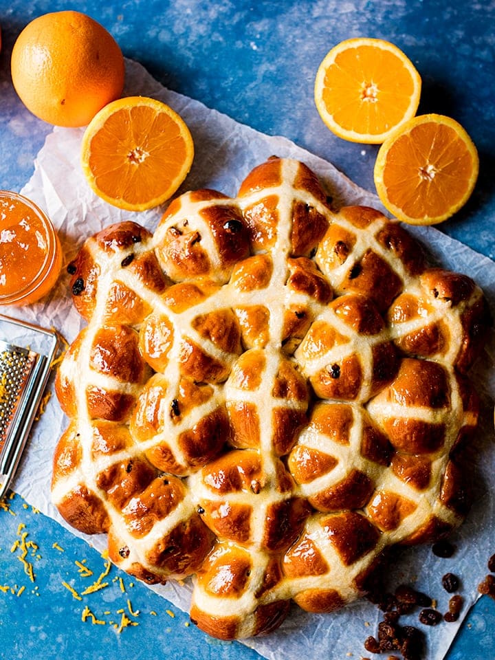 Circle of freshly baked hot cross buns on a blue background