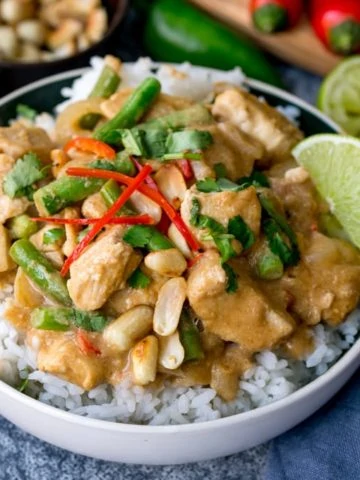 Bowl of rice topped with peanut butter chicken with green beans, chillies and coriander (cilantro)