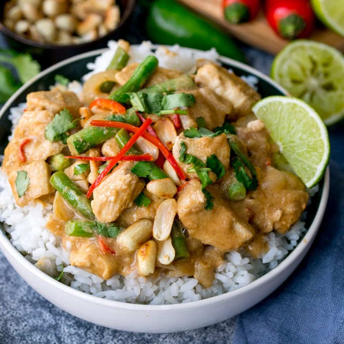 Bowl of rice topped with peanut butter chicken with green beans, chillies and coriander (cilantro)