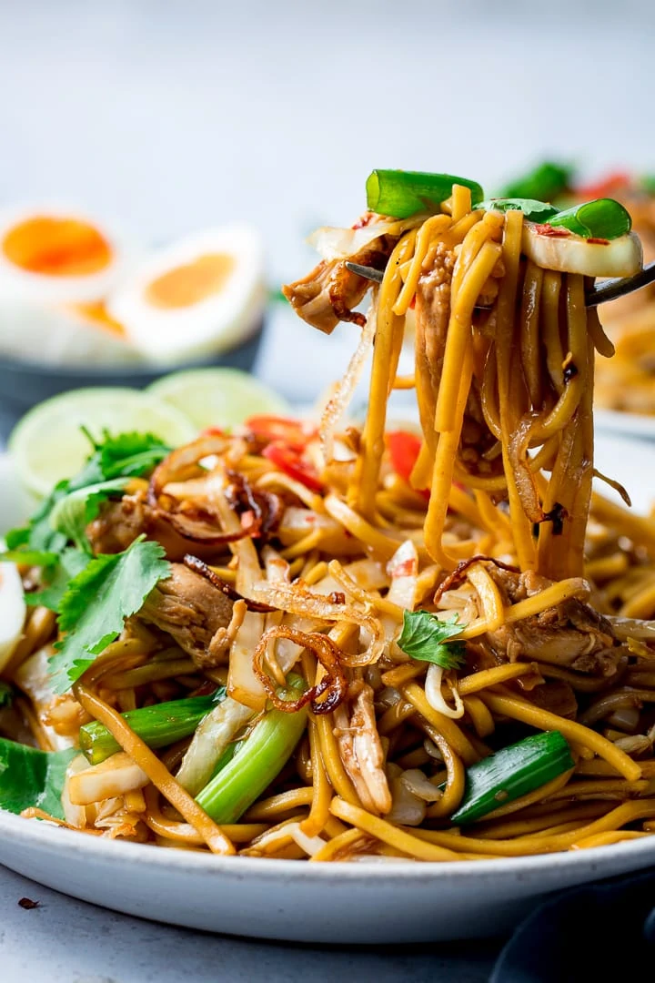 Mee goreng on a plate being lifted with a fork