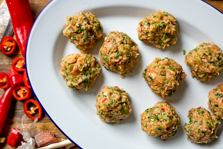 Raw Thai fishcake balls on a white plate