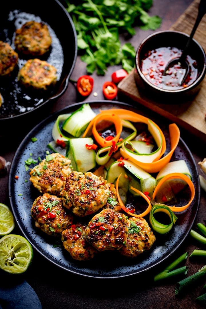 Thai Fishcake Bites on a black plate with vegetable ribbons and ingredients scattered around