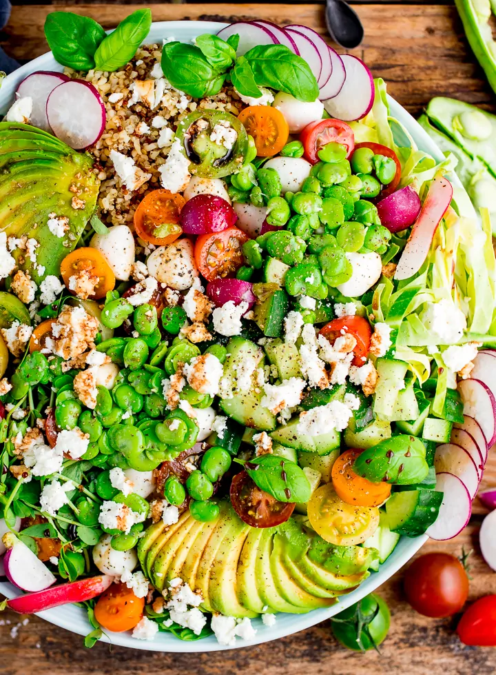 Close up image of broadbean and quinoa caprese salad on a wooden board