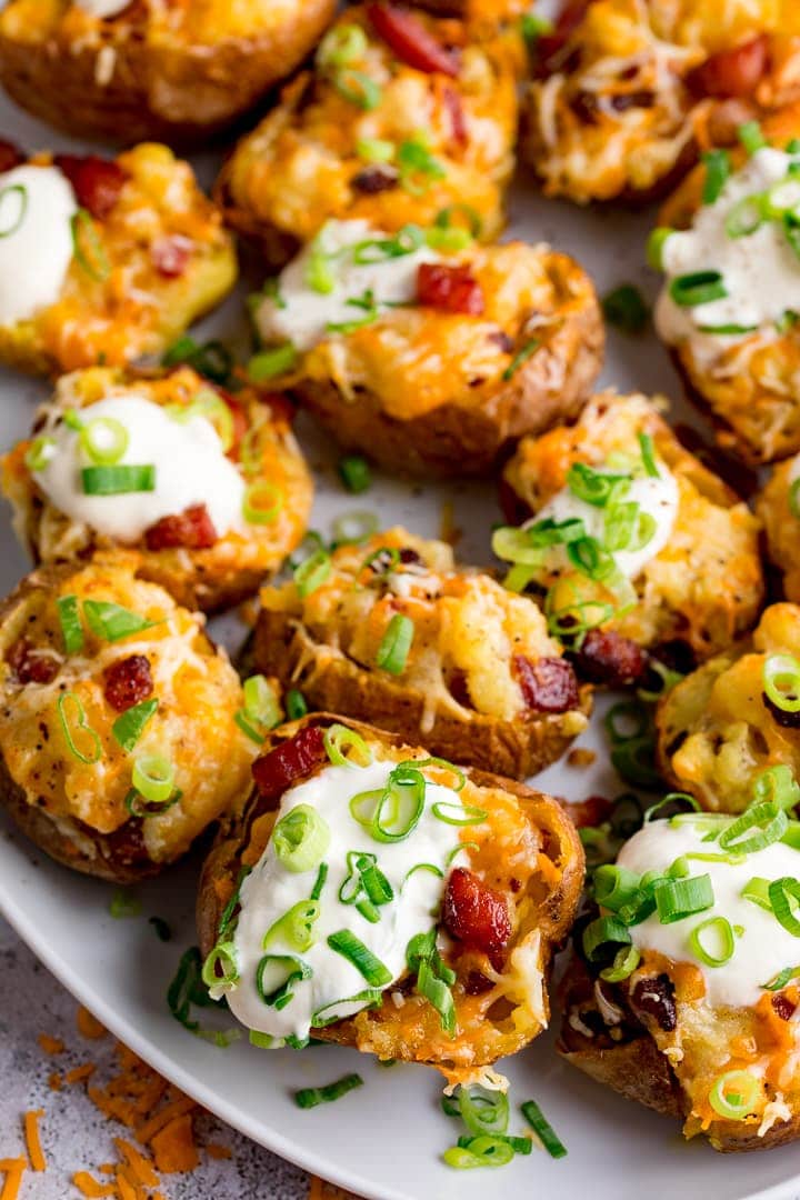 bacon and cheese potato skins on a white plate with sour cream and spring onions