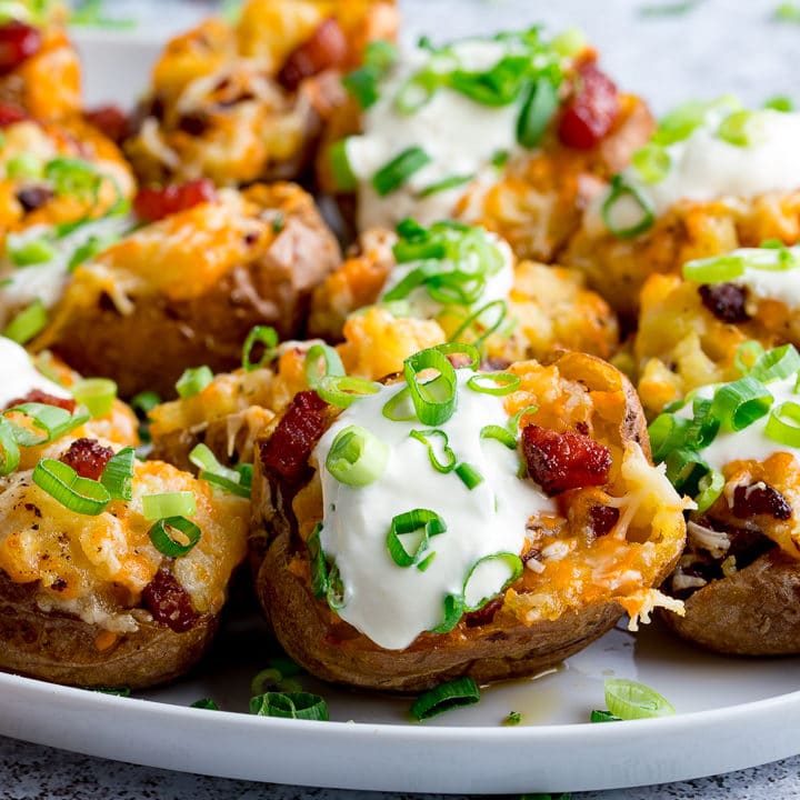 Bacon and cheese potato skins on a plate with sour cream and spring onions