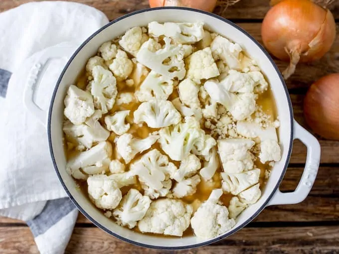 cauliflower, stock and onions on a pan