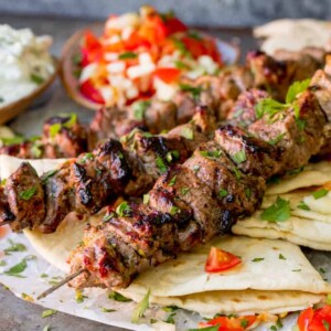 Square image of Lamb souvlaki kebabs on top of toasted breads