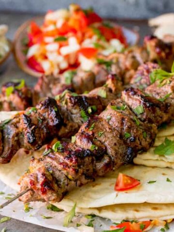 Square image of Lamb souvlaki kebabs on top of toasted breads