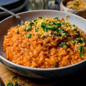 Bowl of creamy tomato risotto topped with crispy crumbs and parsley