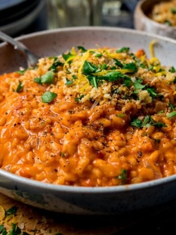 Bowl of creamy tomato risotto topped with crispy crumbs and parsley
