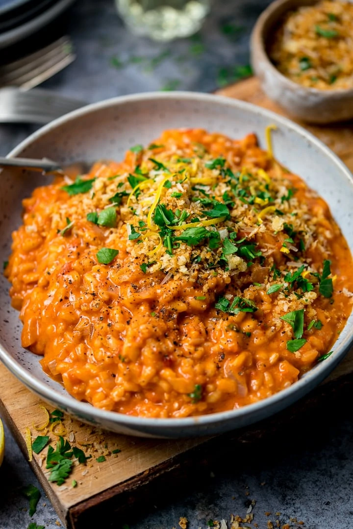 Bowl of tomato risotto on a wooden board