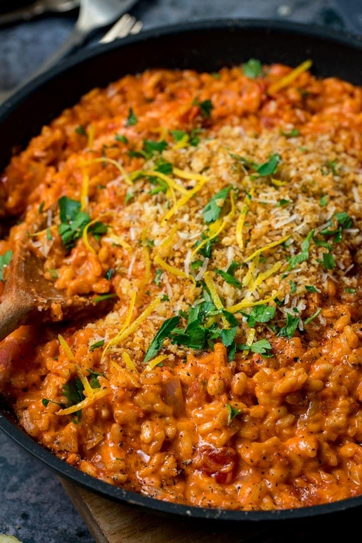 Pan of tomato risotto topped with crispy crumbs, parsley and lemon zest