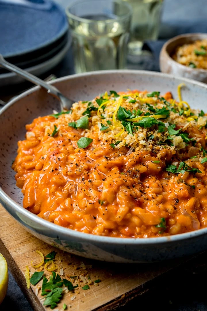 Blue bowl filled with tomato risotto and topped with crispy garlic crumbs