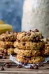 Pile of banana oat chocolate chip cookies on a wooden background.