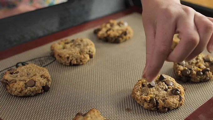 Adding extra chocolate chips to warm banana oat cookies.