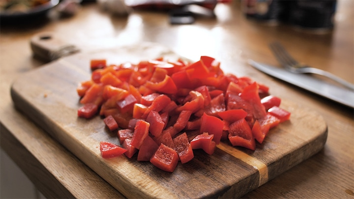 Chopping board with chopped red bell peppers on
