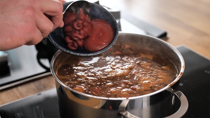 Tomato puree and ketchup being added to a pan of chilli con carne