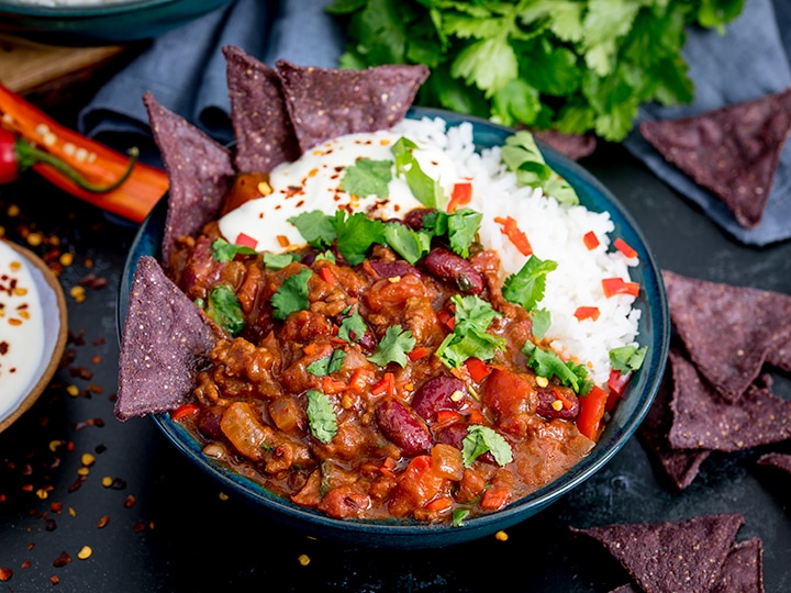 Bowl of chilli con carne with rice and blue corn chips