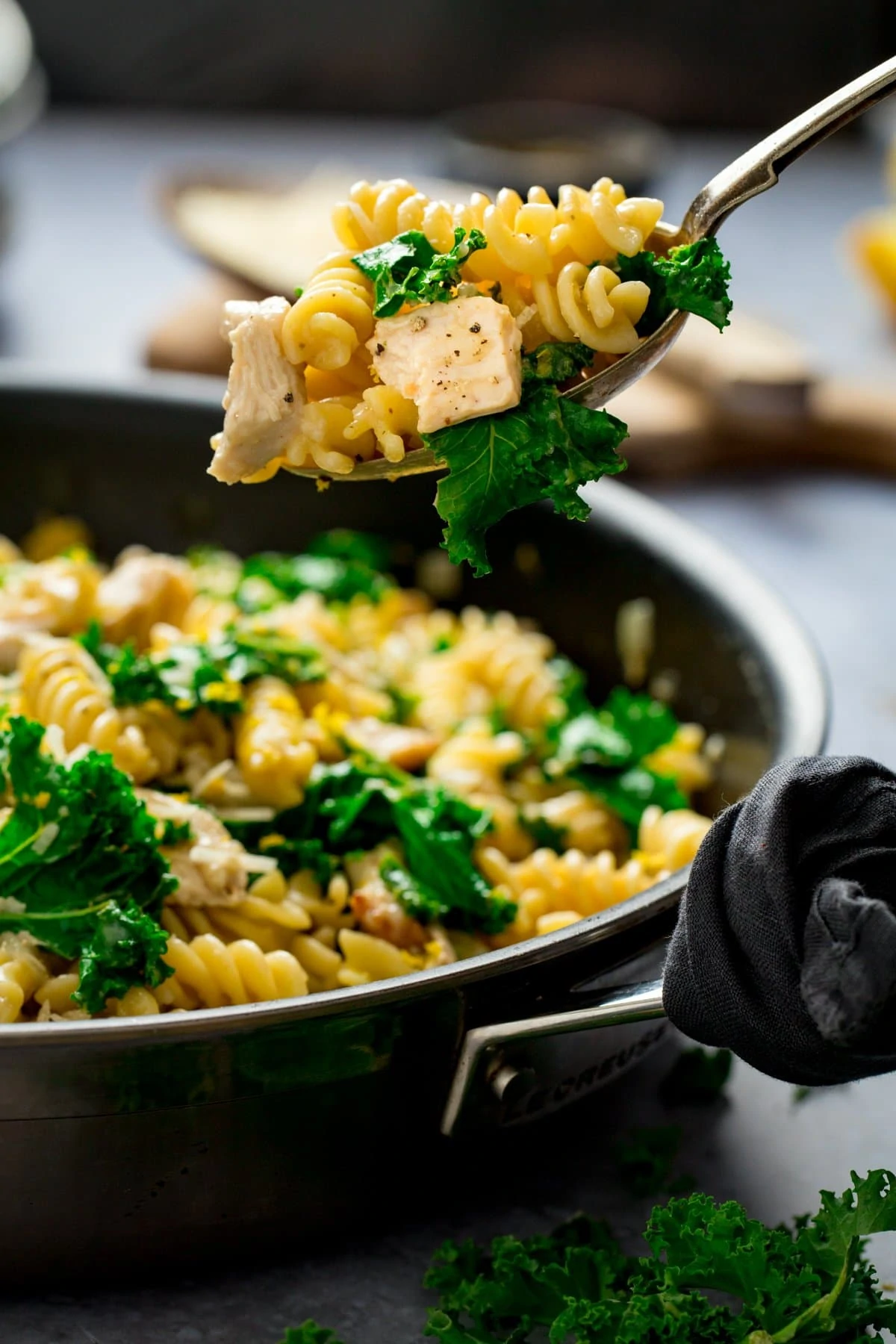 Spoonful being taken from a pan of chicken, kale and pasta
