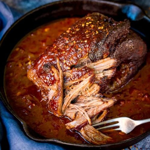 Square image of pulled beef brisket being shredded with a fork