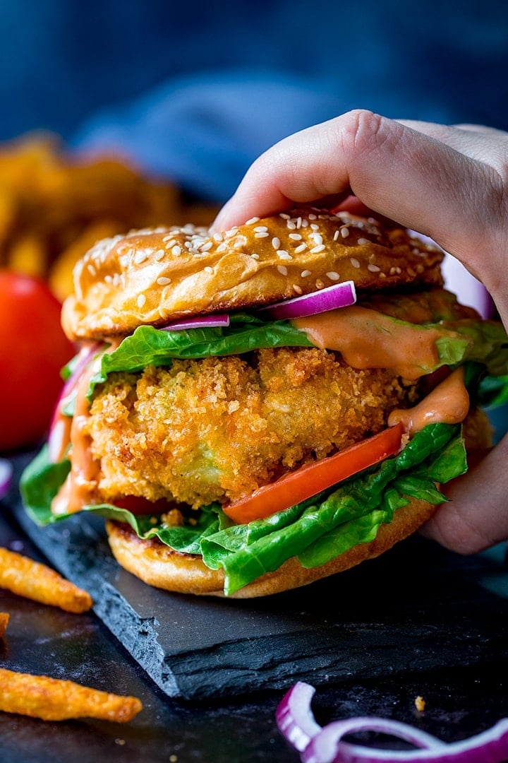 Hand holding a cheesy veggie burger