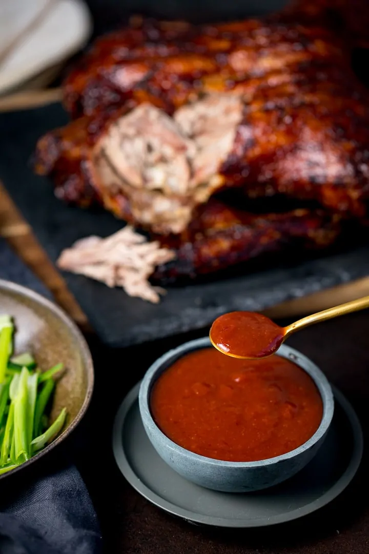 spoonful of plum sauce being taken from a small bowl