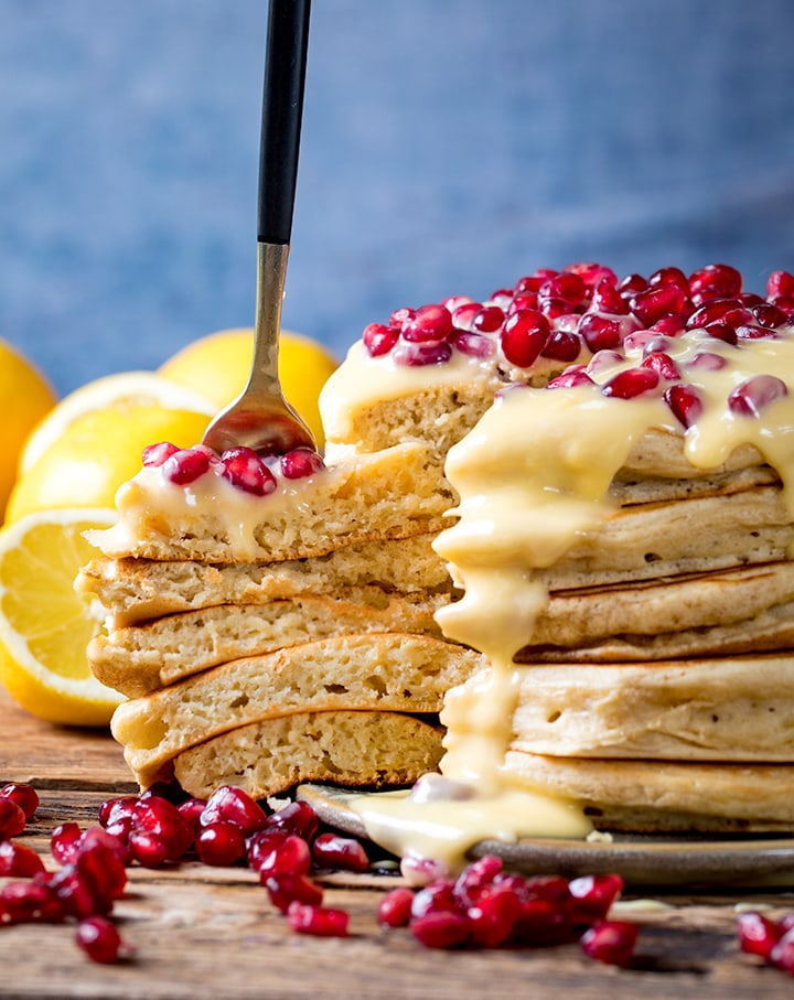 Slice being taken out of a stack of ricotta pancakes with lemon sauce