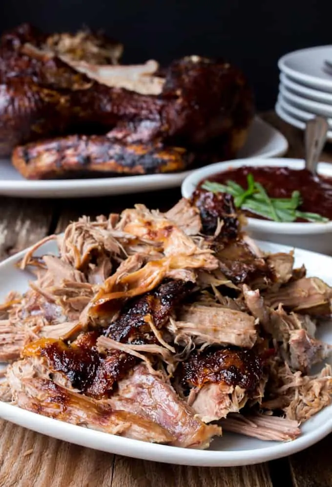 Overhead of Chinese crispy duck on a dark background with plum sauce and greens