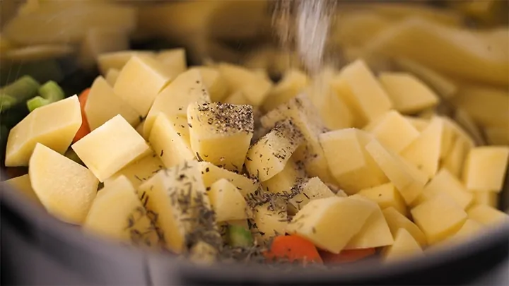 Seasoning vegetables and chicken in a pan for pot pie soup