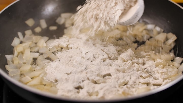 Adding flour to onions in a pan for a soup base