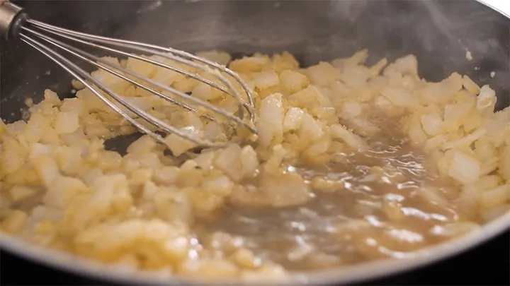 Mixing onions, flour and stock for a soup base