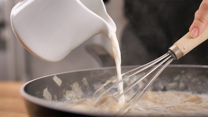 Pouring milk into a pan for pot pie soup