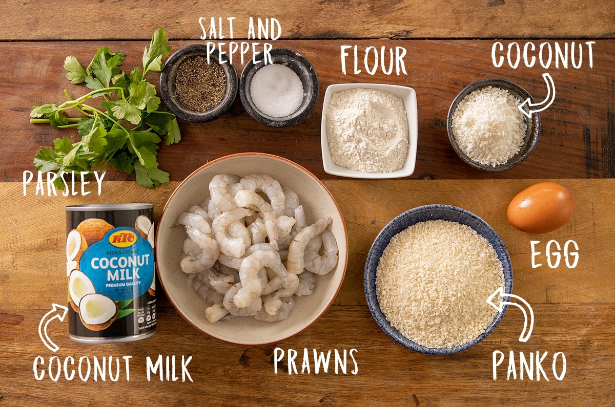 Ingredients for coconut shrimp on a wooden table