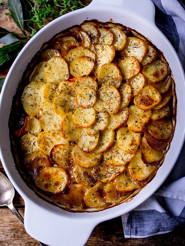 Overhead of Lancashire hotpot on wooden background with blue and white tea towel