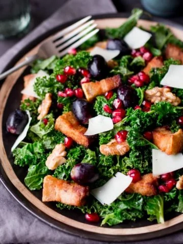 Comforting warm kale salad with crisp slow-cooked pork belly & pomegranate dressing