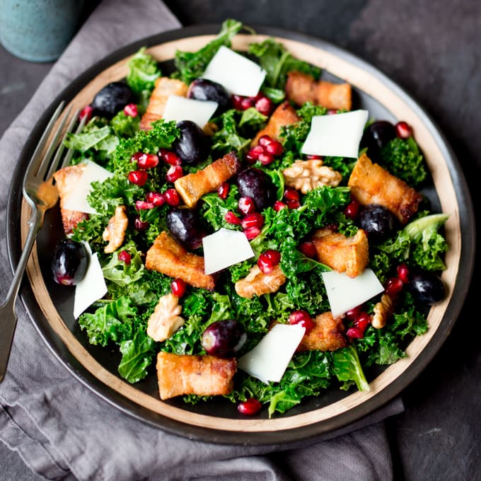Comforting warm kale salad with crisp slow-cooked pork belly & pomegranate dressing