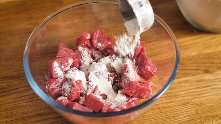 Coating cubes of beef in flour for a steak pie