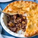 Square image ofr steak and potato pie with slice taken out