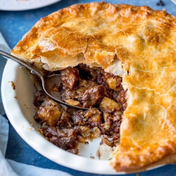 Square image ofr steak and potato pie with slice taken out