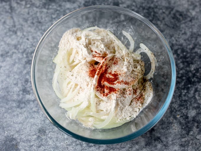 Onions in a bowl with flour, salt, pepper and paprika