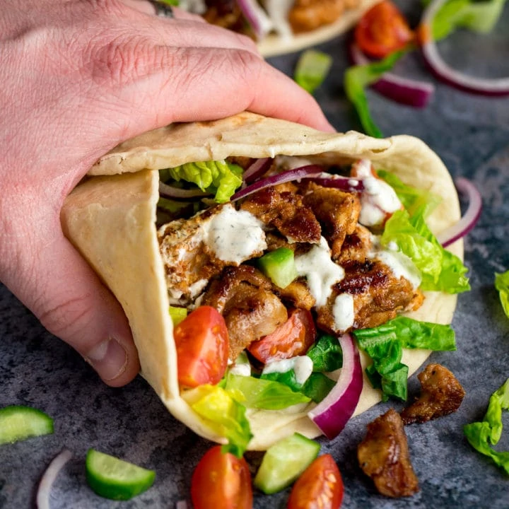 Chicken Shawarma in a pita being held by a hand