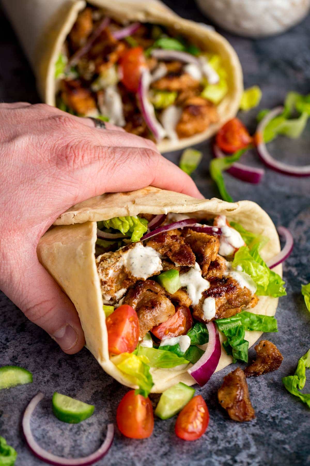 Chicken Shawarma in a pita bread being help by a hand