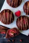 Tall image of mini chocolate cakes with fresh raspberry and Nutella centre, drizzled with Nutella.