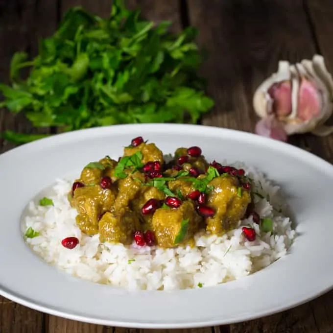 White bowl with rice and Persian Chicken topped with pomegranate seeds