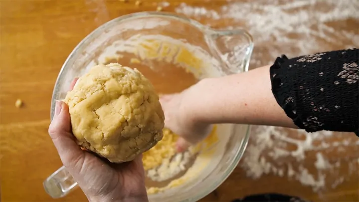 shortbread dough being formed into a ball in hands