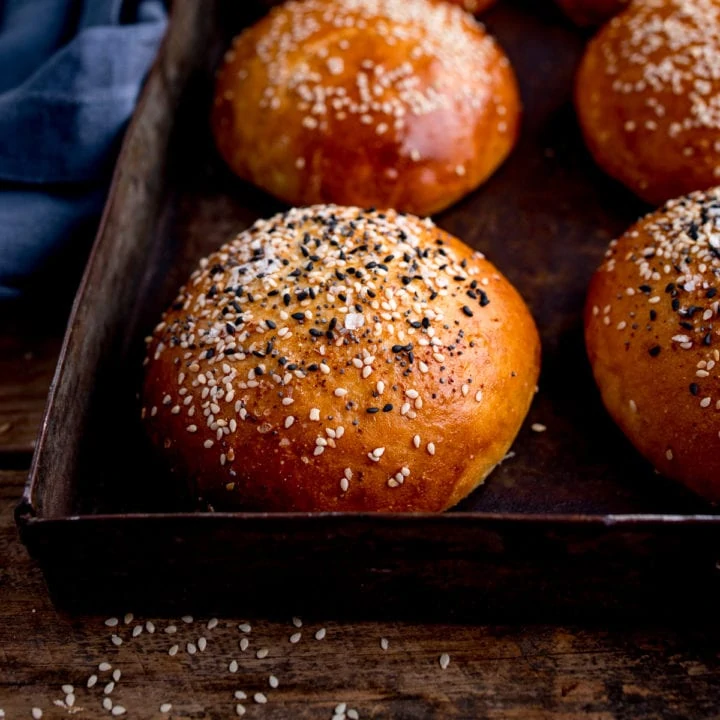 square image of seeded brioche buns on a tray